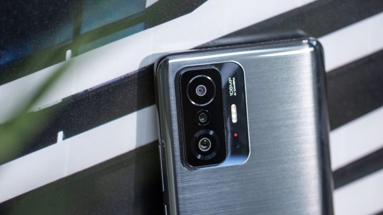 Ein Redmi 11T Pro steht an ein Bild gelehnt, gut sichtbar sind die drei Linsen des Smartphones.