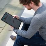 Eine Person sitzt auf einer Treppe und schaut auf ein iPad Pro.