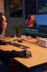 Eine Person sitzt an einem Schreibtisch, auf dem ein Mac Studio und das Studio Display stehen.