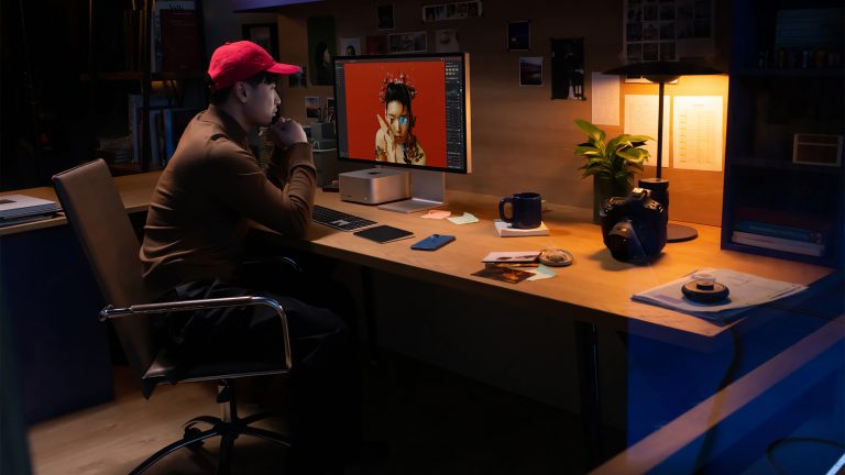 Eine Person sitzt an einem Arbeitsplatz mit Mac Studio und Studio Display und bearbeitet ein Video.