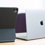 Ein Macbook und ein iPad mit Magic Keyboard stehen auf einem Tisch nebeneinander.