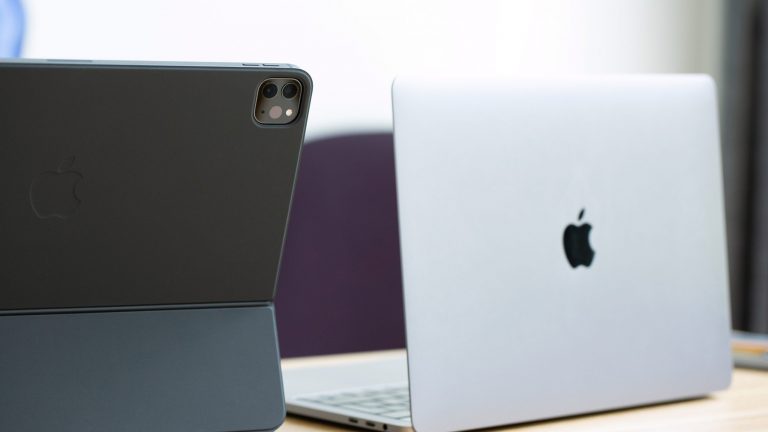 Ein Macbook und ein iPad mit Magic Keyboard stehen auf einem Tisch nebeneinander.