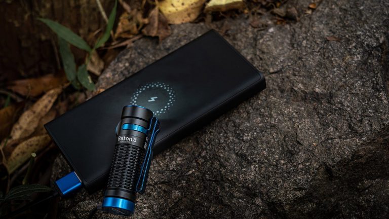 Eine Outdoor-Taschenlampe liegt zusammen mit einer Powerbank auf einem großen Stein im Freien.