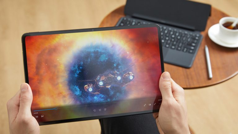 Eine Person hält ein MateBook E von Huawei in der Hand. Im Hintergrund ist Zubehör zu sehen.