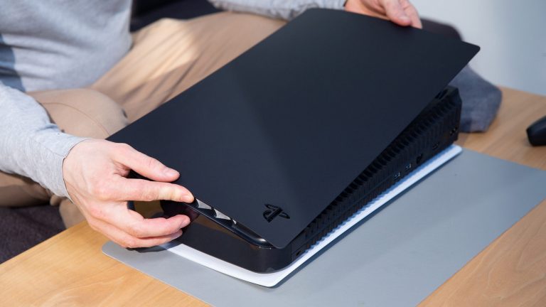Eine Person schiebt ein schwarzes Seitenteil auf eine liegende PlayStation 5.
