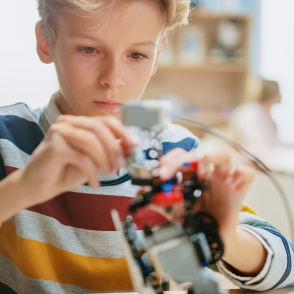 Ein Schulkind sitzt konzentriert vor einem Lernroboter.