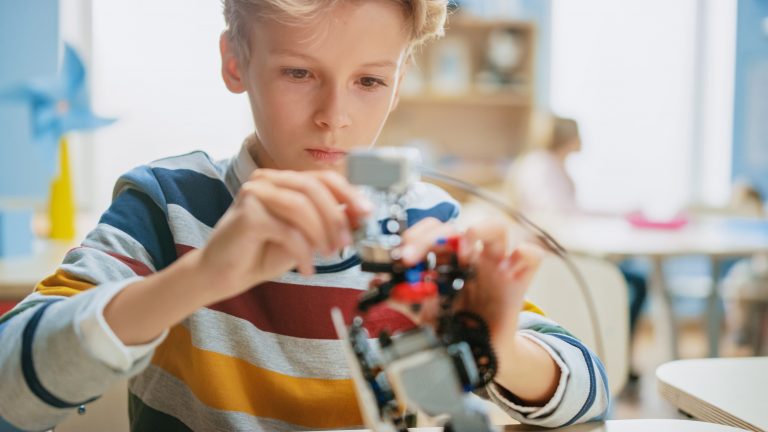 Ein Schulkind sitzt konzentriert vor einem Lernroboter.