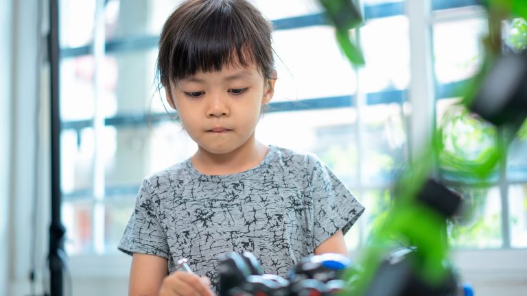 Ein Kind spielt mit einem Roboter.