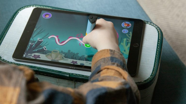 Eine Kinderhand zeichnet mit einem Edurino-Stift auf einem Tablet, auf dem die Edurino-App läuft.