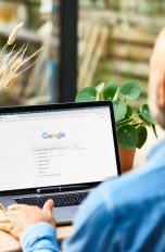 Eine Person sitzt vor einem Laptop, auf dem die Google-Suchmaske zu sehen ist.