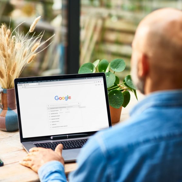 Eine Person sitzt vor einem Laptop, auf dem die Google-Suchmaske zu sehen ist.