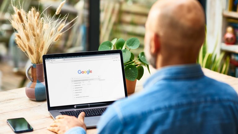 Eine Person sitzt vor einem Laptop, auf dem die Google-Suchmaske zu sehen ist.