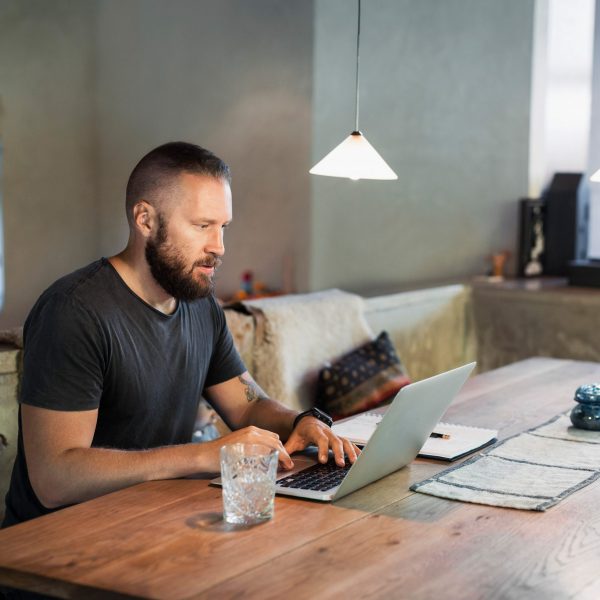 Eine Person sitzt mit ihrem Laptop am Tisch.