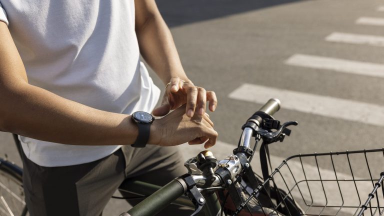 Eine Person sitzt auf einem Fahrrad und trägt eine Google Pixel Watch am rechten Handgelenk.