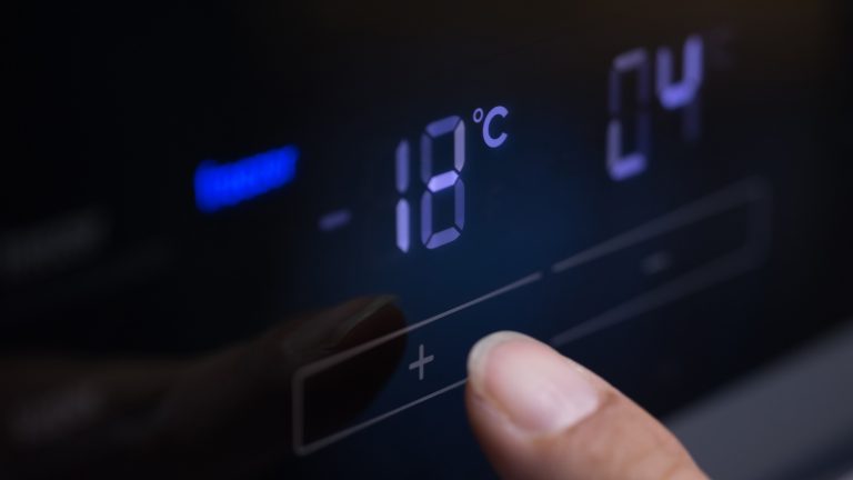Ein Zeigefinger betätigt die Temperatureinstellung an einem Kühlschrank.