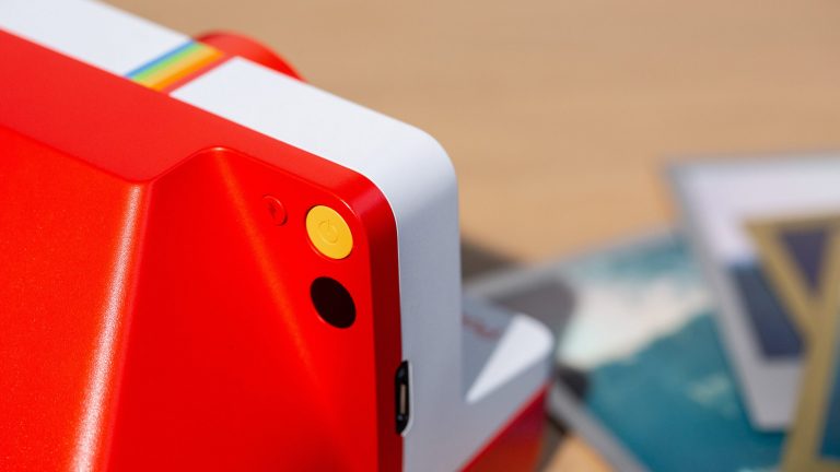 Detailaufnahme der Rückseite einer Polaroid-Kamera. Zu erkennen sind unter anderem die Taste für den Auslöser und den Blitz.