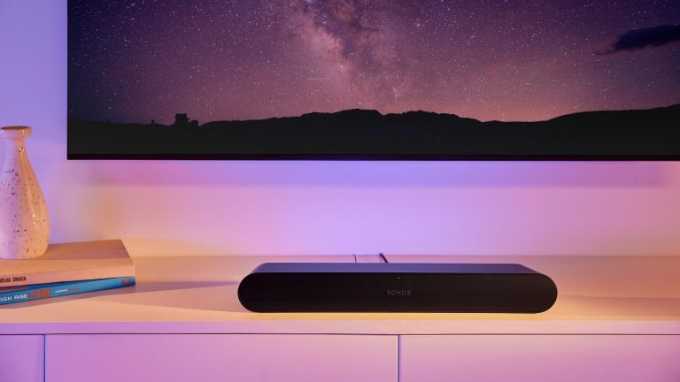 Die Soundbar Sonos Ray liegt auf einem weißen TV-Schrank.