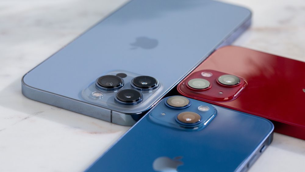 Das iPhone 13 liegt in drei unterschiedlichen Farben und Größen auf einem Tisch.