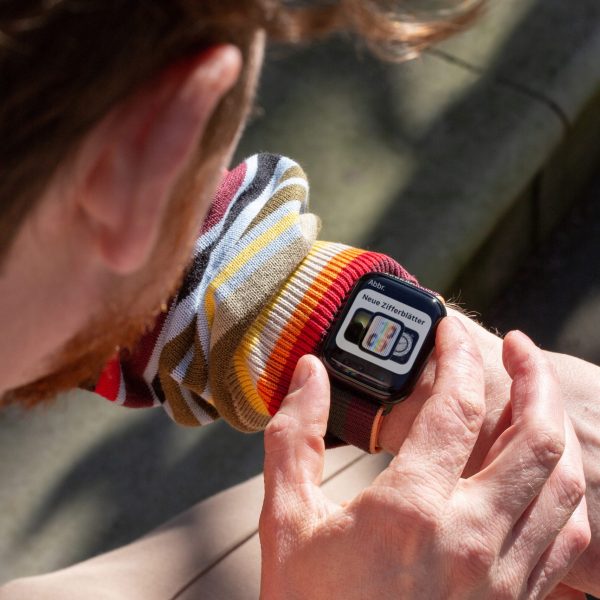 Eine Person blickt auf die Apple Watch, die sie am linken Arm tr&auml;gt und stellt sie ein.