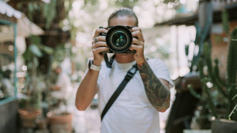 Eine Person hält blickt durch den Sucher einer Kamera mit großem Objektiv, um ein Foto aufzunehmen.