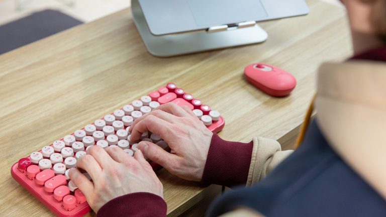 Eine Person tippt auf einer rosafarbenen Logitech Pop Keys.
