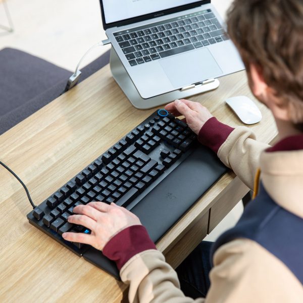Eine Person sitzt an einem Schreibtisch vor einer Razer Huntsman V2.