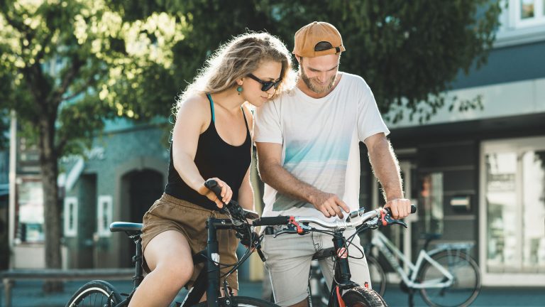 Zwei Personen auf Fahrrädern schauen auf ein Smartphone, das an einem der beiden Lenker befestigt ist.