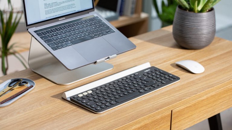Eine Logitech K780 liegt vor einem MacBook Pro. Neben der Tastatur liegt eine Apple Magic Mouse.