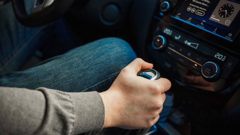 Eine Person betätigt die Gangschaltung in ihrem Auto.