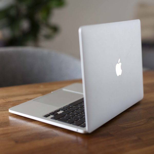 Ein MacBook steht ge&ouml;ffnet auf einem Schreibtisch.
