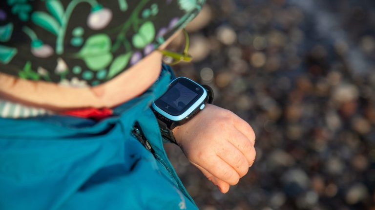 Ein Kind trägt eine Xplora X5 Play am linken Handgelenk und schaut darauf.