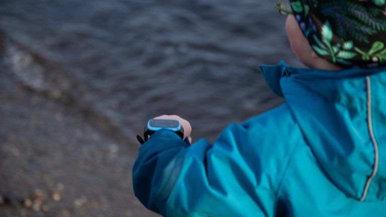 Ein Kind läuft mit einer Xplora X5 Play über einen Strand.