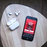 Auf einem kleinen Tisch liegen ein iPhone und AirPods Pro.
