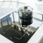 Ein Topf steht auf einem Induktionskochfeld in einer weißen Küche.