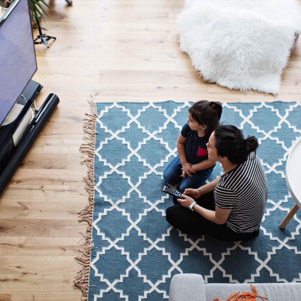 Eine Person sitzt mit einem Kind vor einem Fernseher.