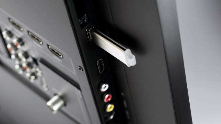 Ein USB-Stick steckt in einem USB-Port an einem Fernseher.