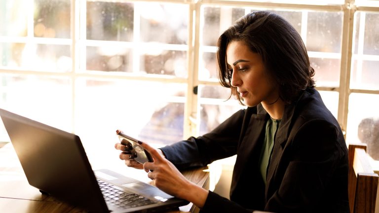 Eine Person hält die Kamera eines Handys in Richtung eines Laptop-Bildschirms, um einen QR-Code zu scannen.