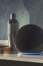 Ein Echo Dot steht auf einem Sideboard neben einigen Gläsern und einem Cocktailshaker.