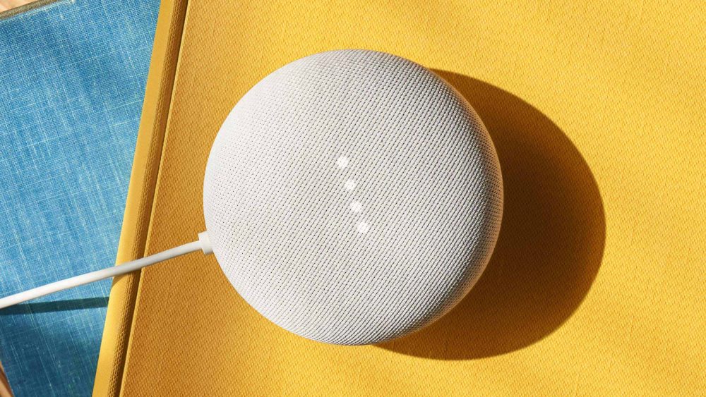 Ein Google Nest Mini steht auf einer gelben Oberfläche.
