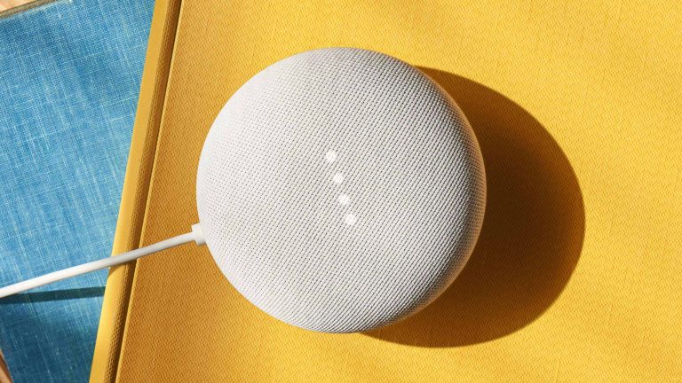 Ein Google Nest Mini steht auf einer gelben Oberfläche.