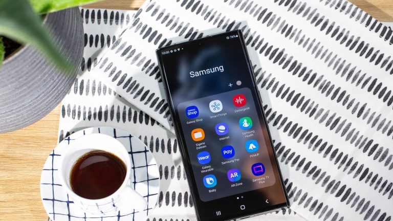 Ein Samsung Galaxy S22 Ultra liegt mit dem Display nach oben auf einer Tischdecke. Daneben steht eine Tasse Kaffee.