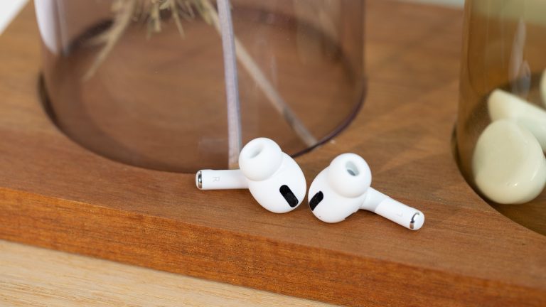 Zwei AirPods Pro liegen nebeneinander auf einer hölzernen Oberfläche.