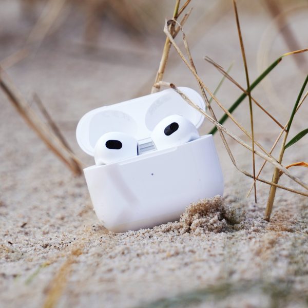 AirPods der dritten Generation in ihrem Case liegen auf einer Sandbank.