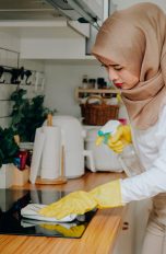 Ceranfeld reinigen Eine Person reinigt ein Ceranfeld mit Glasreiniger und einem Tuch.