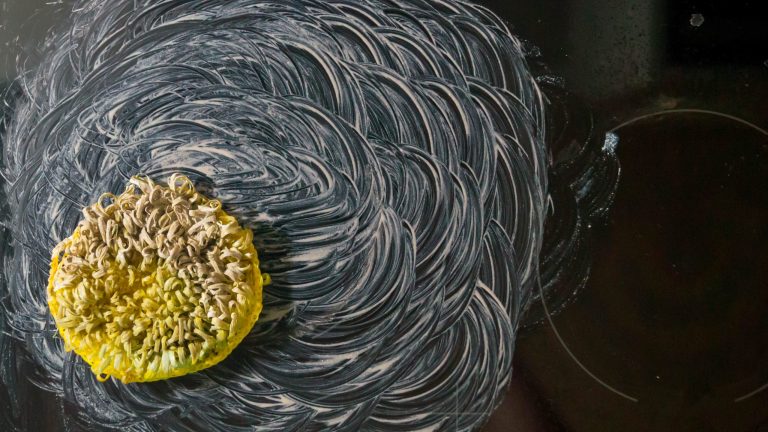 Ein Schwamm liegt auf einem eingeseiften Ceranfeld.