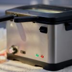 Eine Fritteuse steht auf einer Tischdecke.