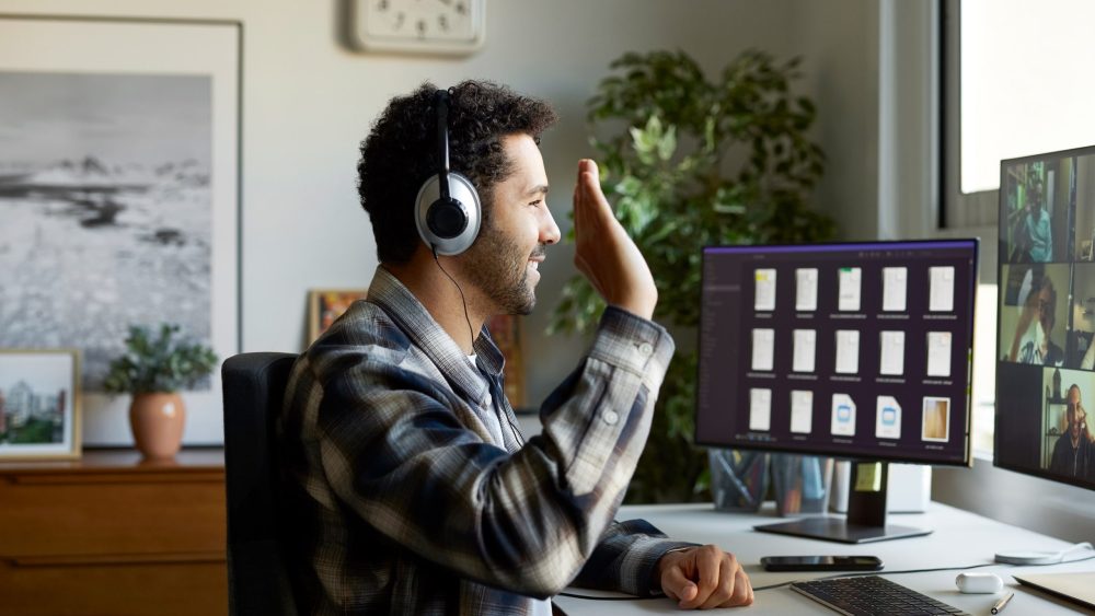 Eine Person sitzt vor einem Bildschirm und führt einen Video-Call mit einer Gruppe.