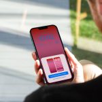 Eine Person hält ein iPhone in der Hand, auf dem gerade die Einstellungsoptionen des Sperrbildschirms zu sehen sind.