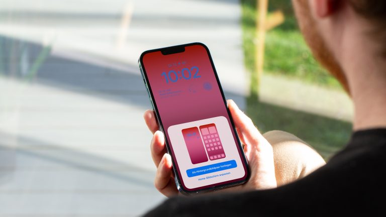 Eine Person hält ein iPhone in der Hand, auf dem gerade die Einstellungsoptionen des Sperrbildschirms zu sehen sind.