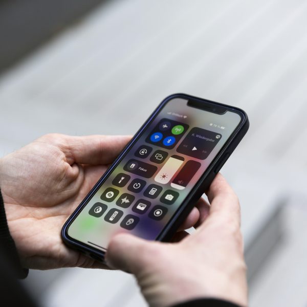 Eine Person h&auml;lt ein iPhone 12 in den H&auml;nden, auf dem gerade das Kontrollzentrum zu sehen ist.